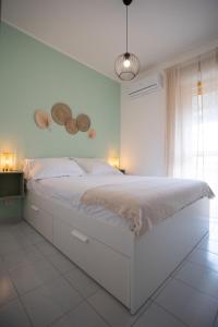 een slaapkamer met een groot wit bed met 2 manden aan de muur bij Pausa Mare Seaside in Torre a Mare