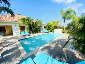 a swimming pool in front of a house with palm trees at Endless Summer in Palm-Eagle Beach