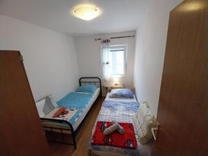 a small room with two beds and a window at Apartmani Jadran in Mali Lošinj