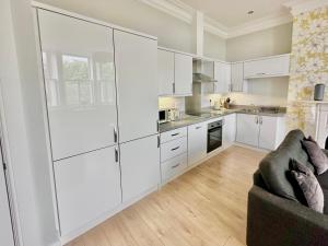 a white kitchen with white cabinets and a couch at Moorgate View - Free on street Parking in York