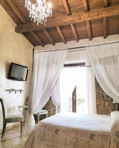 1 dormitorio con 1 cama con lámpara de araña y ventana en Antico Casale Fabrizi, en Velletri