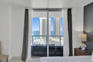 a bedroom with a window with a view of the ocean at Stunning Beach Resort Large 4BR 3BA Condo 24 FL in Hallandale Beach +60 photos