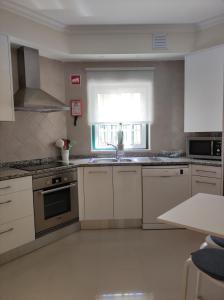 eine Küche mit weißen Schränken und einer Spüle und einem Fenster in der Unterkunft Casa Brisa do Mar in Porches