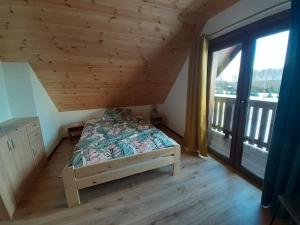 a bedroom with a bed and a large window at Agroturystyka '' U Adasia i Marysi '' - Domek nad jeziorem in Dębogóry