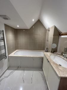 a white bathroom with a tub and a sink at Close to Goodwood- Dogs Welcome -3 beds & Parking in Petworth