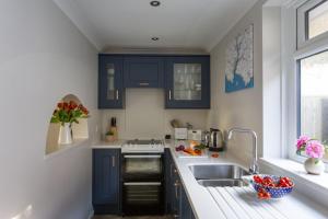 una cocina con armarios azules y fregadero en Prawn Cottage en Hope-Cove