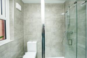 a bathroom with a toilet and a glass shower at Newly Renovated Modern 4 Bed 3 Bath Apartment London in London