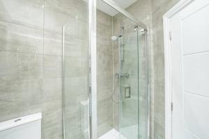 a shower with a glass door in a bathroom at Newly Renovated Modern 4 Bed 3 Bath Apartment London in London