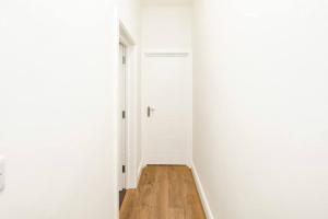 einen leeren Flur mit weißer Tür und Holzboden in der Unterkunft Newly Renovated Modern 4 Bed 3 Bath Apartment London in London