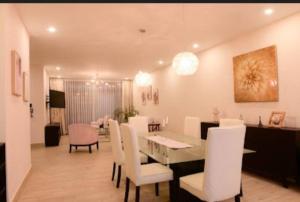 a dining room with a table and white chairs at Casa Tikal cerca de aeropuerto in Flores