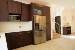 a kitchen with brown cabinets and a stainless steel refrigerator at Casa Tikal cerca de aeropuerto in Flores