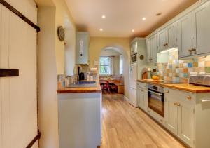 a large kitchen with white cabinets and wooden floors at Monks Bridge in Crosby Ravensworth