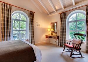 um quarto com uma cama, uma cadeira e janelas em Monks Bridge em Crosby Ravensworth