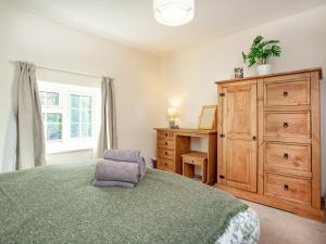 a bedroom with a bed with a chair and a dresser at Otters Cottage in Ottery Saint Mary