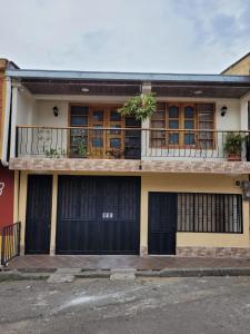 ein Haus mit schwarzen Türen und einem Balkon in der Unterkunft Casa Central, primer piso in Norcasia