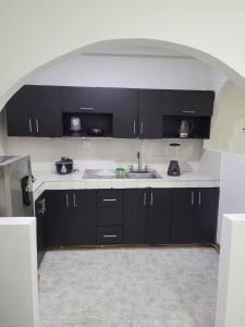 eine Küche mit schwarzen Schränken und einem Waschbecken in der Unterkunft Casa Central, primer piso in Norcasia