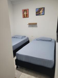 2 Betten in einem Zimmer mit 2 Bildern an der Wand in der Unterkunft Casa Central, primer piso in Norcasia