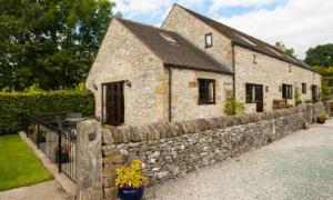 un edificio de piedra con una valla de piedra y un muro de piedra en Bradstones, en Wirksworth