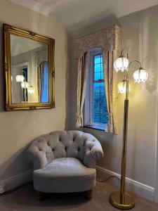 a living room with a chair and a mirror and a lamp at Suburban London Villa with Garden in Kingston upon Thames