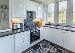 a kitchen with white cabinets and a black and white tile floor at Humbug Lodge in Pateley Bridge