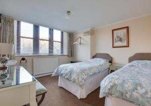 a bedroom with two beds and a desk and windows at Humbug Lodge in Pateley Bridge
