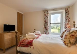 a bedroom with a bed with a television and a window at Three Halfway Houses in Hawes