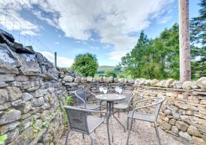 a patio with a table and chairs and a stone wall at Three Halfway Houses in Hawes