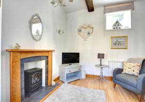 a living room with a fireplace and a tv at Wren Cottage in Middleham