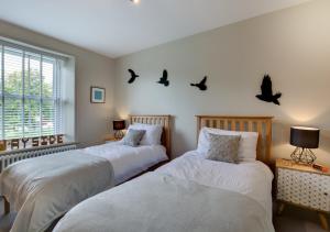 two beds in a room with birds on the wall at Wayside in Carperby