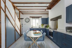 a kitchen with blue cabinets and a white table and chairs at Start Way in Kingsbridge