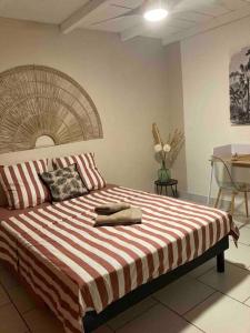 a bedroom with a large bed with a striped blanket at Maison avec spa et jardin in Schœlcher