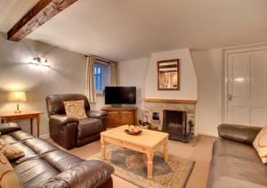 sala de estar con muebles de cuero y chimenea en Barn Owl Cottage, en Masham