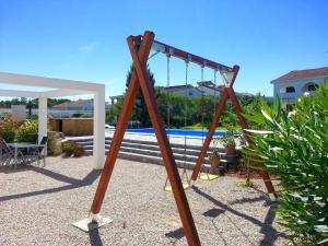 a swing set in a yard with a pool at Apartments Kovacic in Malinska