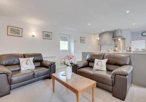 a living room with two leather couches and a coffee table at Ghyllfoot Apartment in Gunnerside