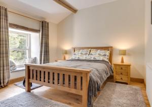 a bedroom with a wooden bed and a window at Baugh Fell View in Cotterdale