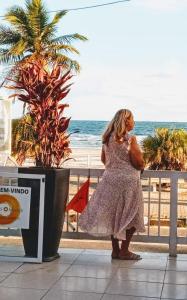 uma mulher de vestido perto da praia em Costa Maris Beach Hotel Frente Mar no Guarujá