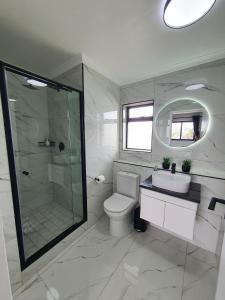 a bathroom with a toilet and a shower and a sink at Knightsbridge Superior Apartments in Cape Town