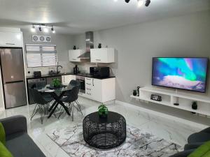 a living room with a tv and a table and a kitchen at Knightsbridge Superior Apartments in Cape Town