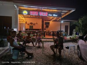 CocoVille Guesthouse في Alegria: مجموعة اشخاص جالسين امام كوفي شوب