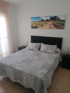 1 dormitorio con 1 cama y una pintura en la pared en Alojamiento las Dunas en Tabernas
