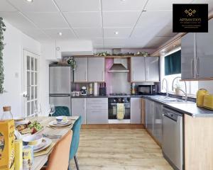 a kitchen with stainless steel appliances and a table at Stunning Tropical Oasis By Artisan Stays I Free Parking I Weekly or Monthly Stay Offer I Sleeps 7 in Southend-on-Sea