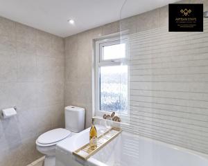 a bathroom with a toilet and a tub and a window at Stunning Tropical Oasis By Artisan Stays I Free Parking I Long Weekend Offer in Southend-on-Sea
