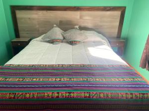 un letto con coperta colorata e cuscini sopra di Casas Particulares, Tipo Cabañas. a San Pedro de Atacama
