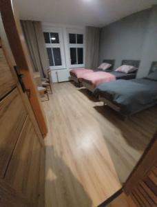 a bedroom with two beds and a wooden floor at Apartament Blisko Granicy in Kunowice