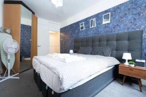 a bedroom with a large bed with a blue wall at Lovely Entire Flat in Kings Cross in London