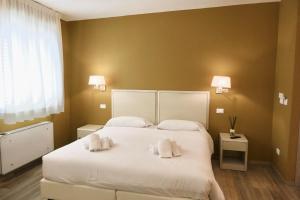1 dormitorio con 1 cama blanca grande y toallas. en Il Gabbani B&B en Marina di Bibbona