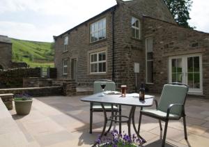 a patio with a table and chairs in front of a building at Throstle Nest House in Gunnerside