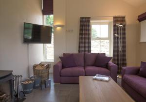 a living room with a purple couch and a tv at Throstle Nest House in Gunnerside