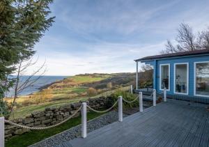 uma casa azul com um deque com vista para o oceano em 1 Browcote Cottage em Ravenscar
