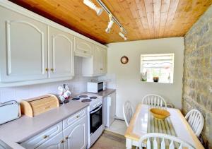une cuisine avec des armoires blanches et un plafond en bois dans l'établissement 2 Bransdale Cottage, à Glaisdale